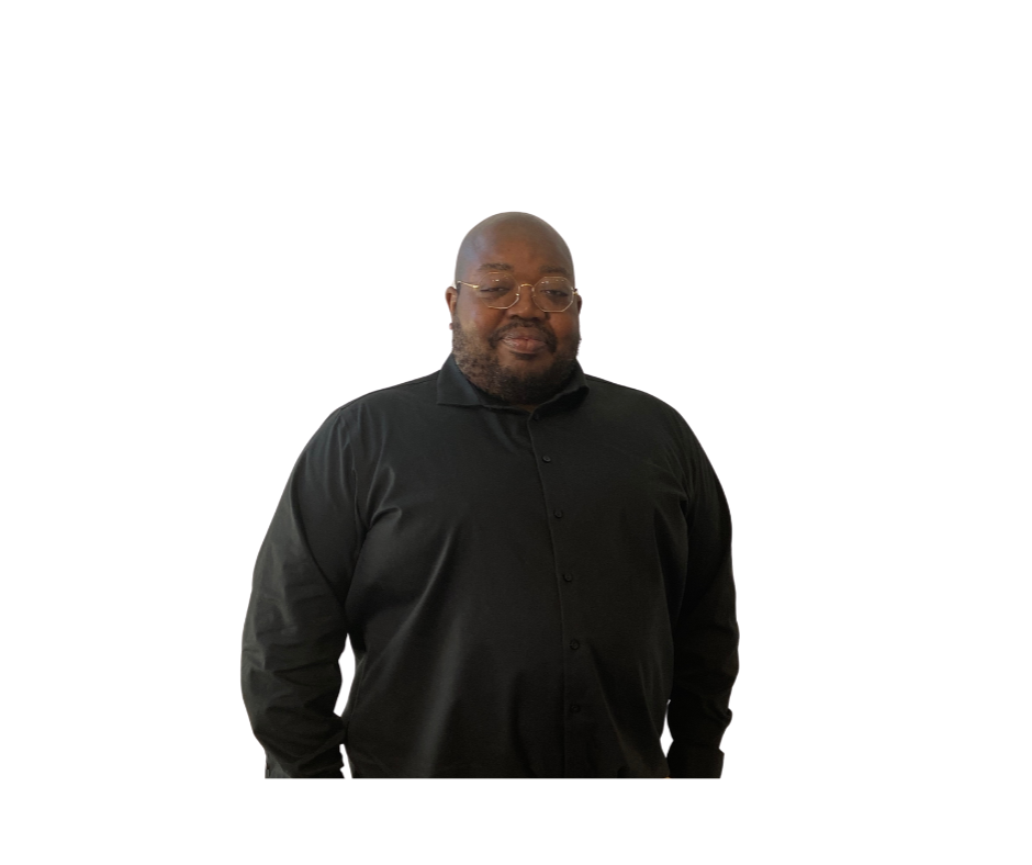 A man in black jacket standing next to white wall.